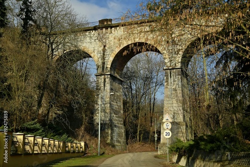 Prague semmering / railway bridge made of stone with tall arches above road with traffic signes on a sunny spring day with clear blue sky