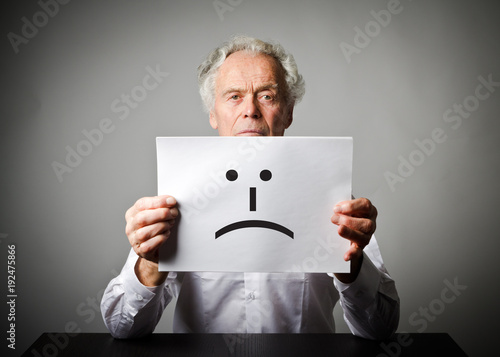 Old man in white is holding white paper with smile. Unhappy concept. photo