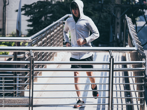 Young athletic man jogging on city bridge at the morning.