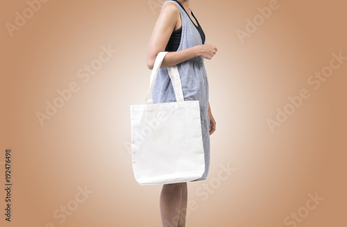 Girl is holding bag canvas fabric for mockup blank template isolated on color background.