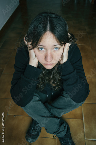 thoughtful girl sitting on the floor with her hands on her head