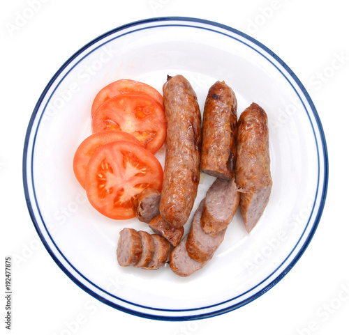 Grilled bratwurst and slice tomato in white plate on white background