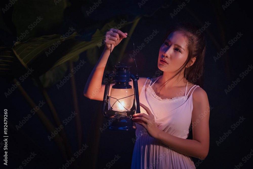 Woman with Vintage Lantern Outside at Night - Cosplay girl in nutral  costume holding a lamp, Young woman in white long dress walking in night  wood foto de Stock | Adobe Stock