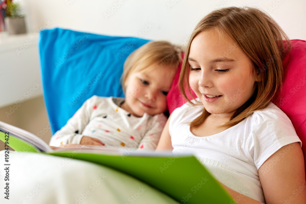 little girls or sisters reading book in bed little girls or sisters reading book in bed