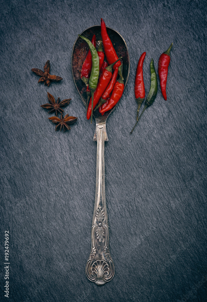 Red and Green Chillies in a spoon on a rustic grey slate background with copy space Red and Green Chillies in a spoon on a rustic grey slate background with copy space