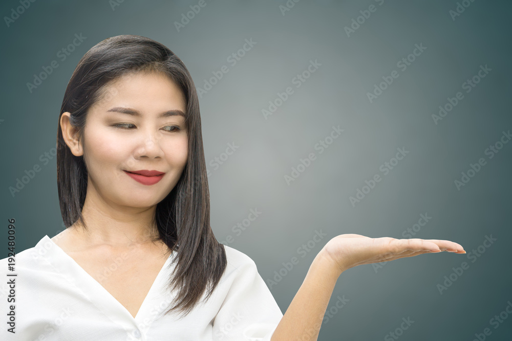 attractive Asian business woman hand showing or presenting something smiling over grey background with copy space attractive Asian business woman hand showing or presenting something smiling over grey background with copy space