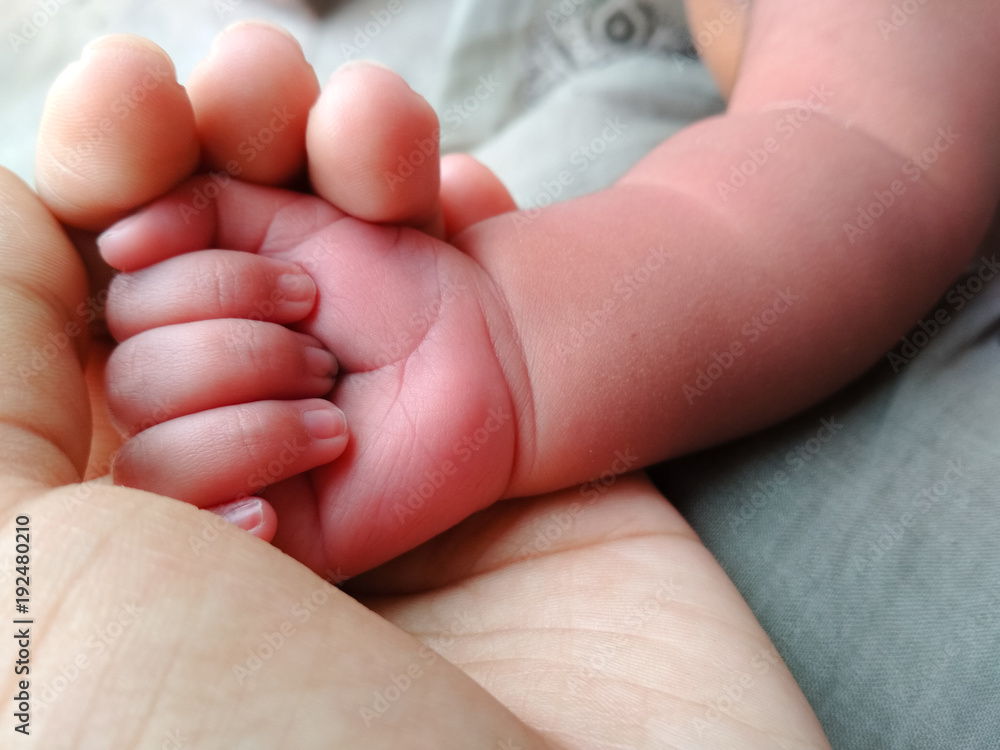 Mother Holding hand of infant showing love and care Mother Holding hand of infant showing love and care