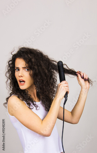 beautiful hair model girl young adult with curly hair and hair iron straightener happy and unhappy concept 
