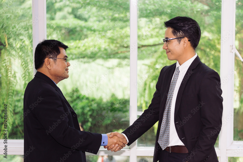 Handshake between old business man and young business man indoor Handshake between old business man and young business man indoor