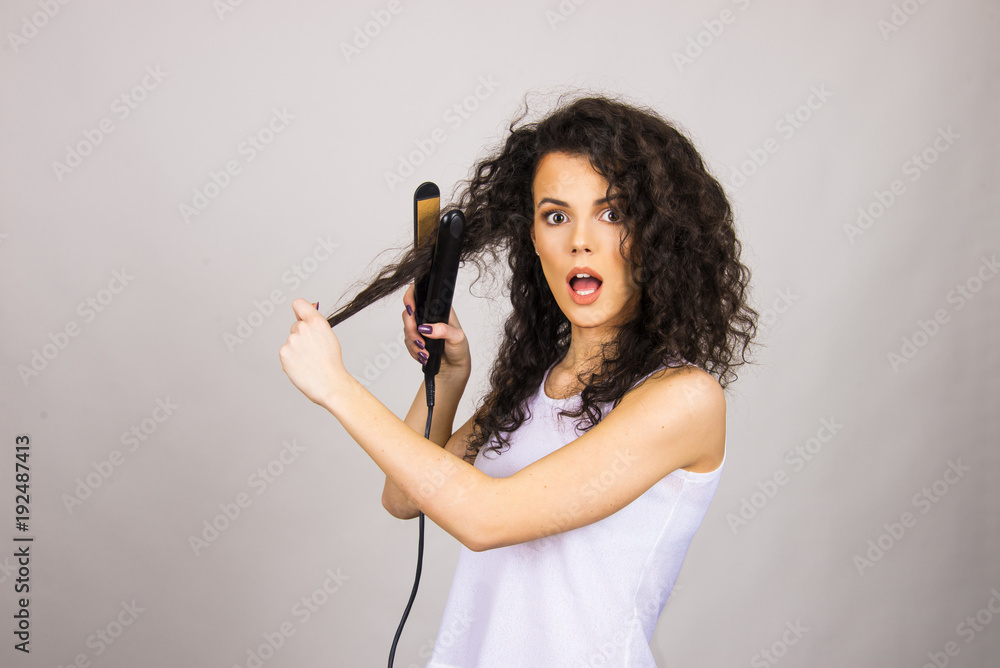beautiful hair model girl young adult with curly hair and hair iron straightener happy and unhappy concept beautiful hair model girl young adult with curly hair and hair iron straightener happy and unhappy concept