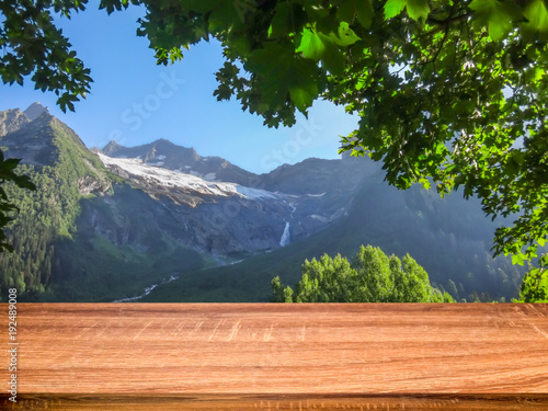 Empty wooden table with blurred background of summer landscape in mountain area. Can be used for display or montage products
