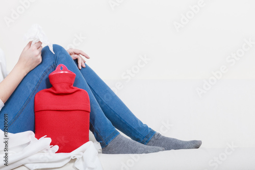 Woman lying on couch with hot water bottle