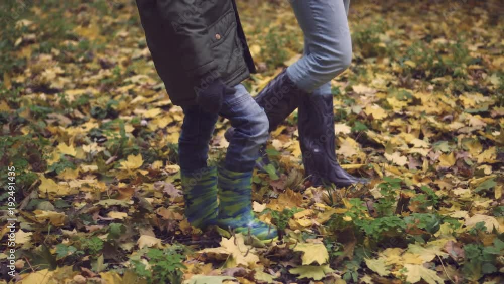 Mother and son walking in rubber boots in autumn forest Mother and son walking in rubber boots in autumn forest