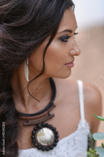 woman in white dress sitting on the beach. bride in Boho style photo