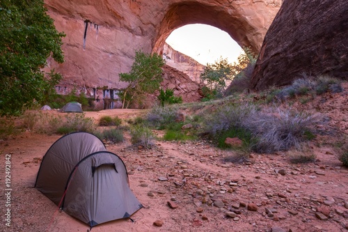 Tent and Wilderness Camping on Great Hiking Trail under Jacob Hamblin Arch in Coyote Gulch, Canyons of the Escalante, Utah, United States photo
