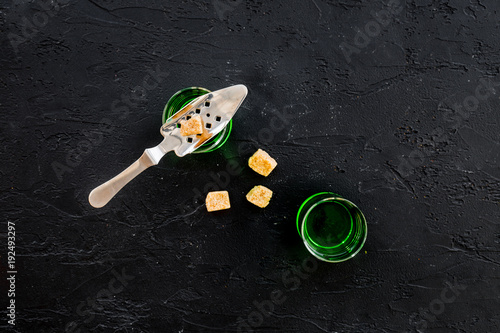 Traditions of drinking absinthe. Special spoon and sugar cubes near shots on black background top view copy space