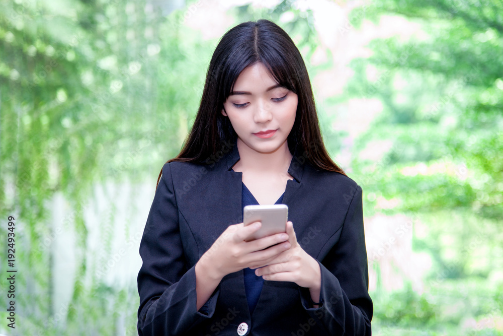 happy asian female watching her photos on cell telephone while relaxing in garden at workplace, charming business woman with beautiful smile reading good news on mobile phone during rest in park. happy asian female watching her photos on cell telephone while relaxing in garden at workplace, charming business woman with beautiful smile reading good news on mobile phone during rest in park.