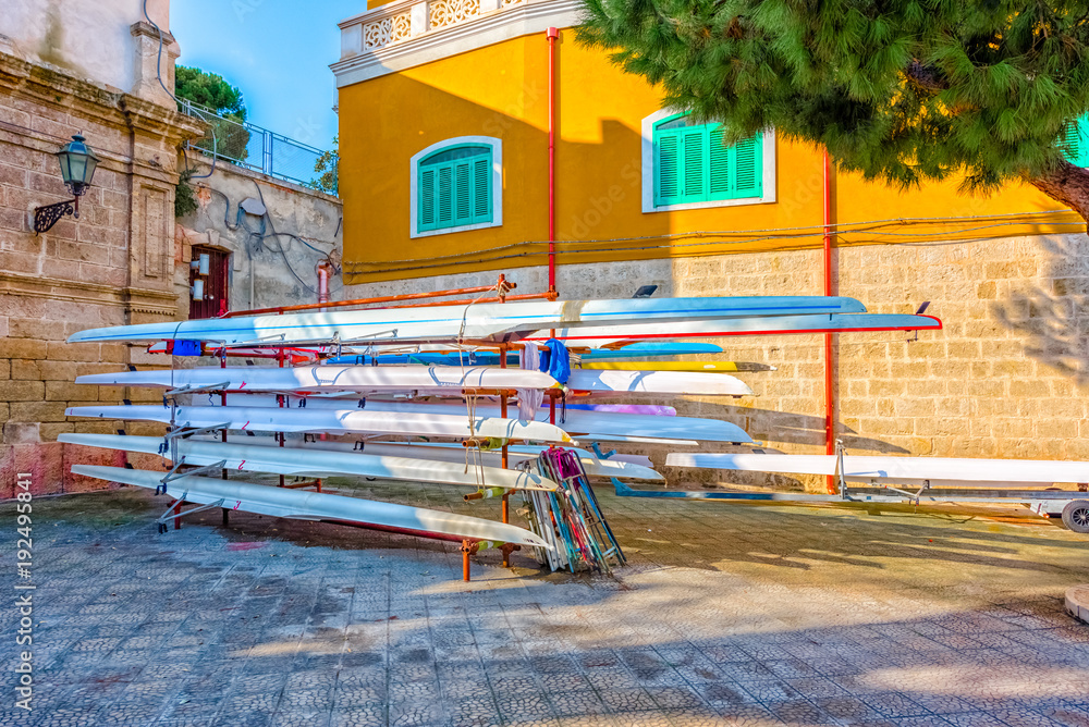 Racing rowing boats standing on metal stand at Monopoli old port.