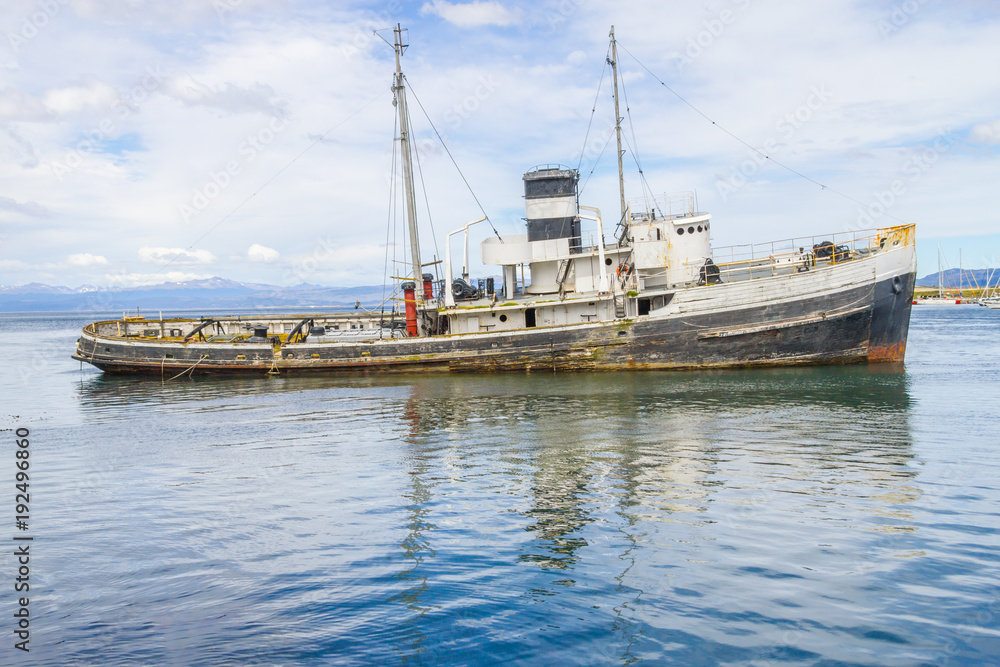 Fototapeta premium Old boat in Beagle channel with mountains in Ushuaia