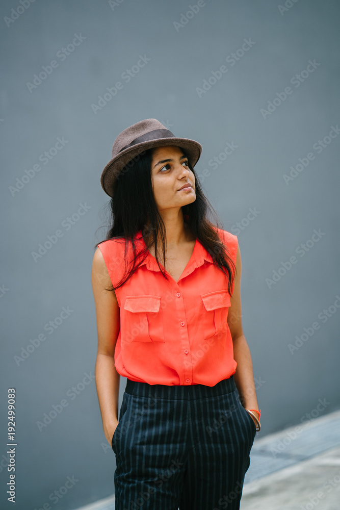 Attractive young professional Indian woman looking up and smiling. She is dressed casually with her hands in her pockets against a grey background. Attractive young professional Indian woman looking up and smiling. She is dressed casually with her hands in her pockets against a grey background.