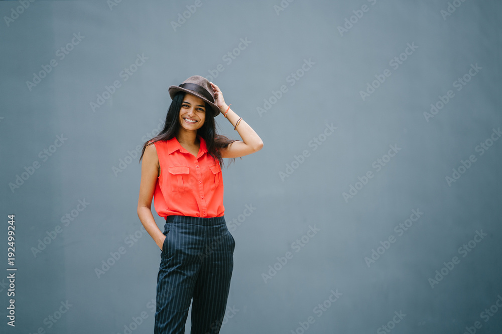 Attractive young professional Indian woman looking up and smiling. She is dressed casually with her hands in her pockets against a grey background. Attractive young professional Indian woman looking up and smiling. She is dressed casually with her hands in her pockets against a grey background.