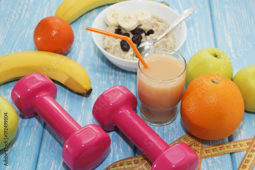 The concept of a healthy diet. Small dumbbells, juice. Bananas. Oranges. Apples. healthy lifestyle. sport. Fitness food. photo