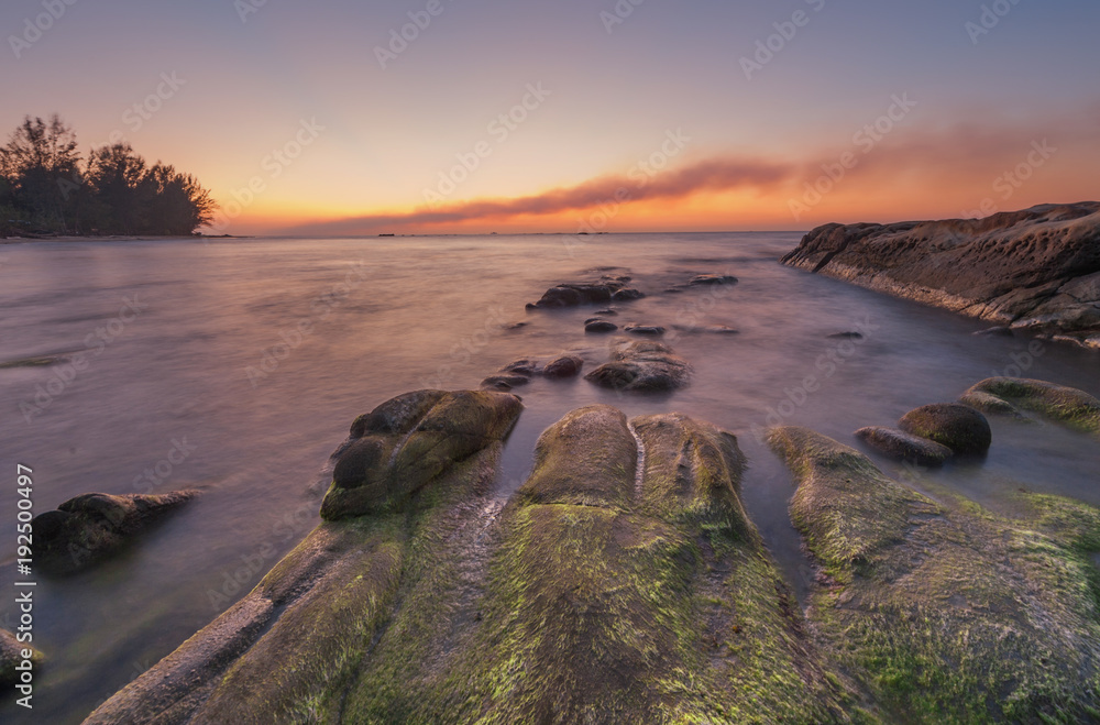 Sunset seascape with coastal rocks covered by green moss at Kudat, Sabah Malaysia.  soft focus due to long expose.