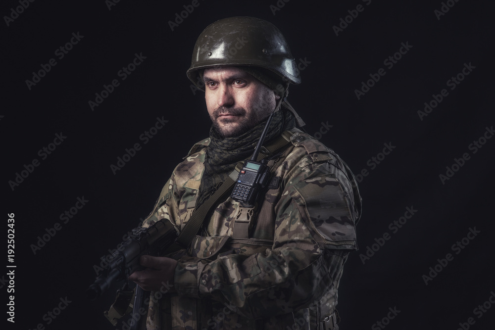 The volunteer on black background with guns and a walkie-talkie The volunteer on black background with guns and a walkie-talkie