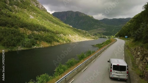 Aerial view on on the cars which are moving by breathtaking mountain road in Norway. Top view, green background full in trees and grass. 4k footage.