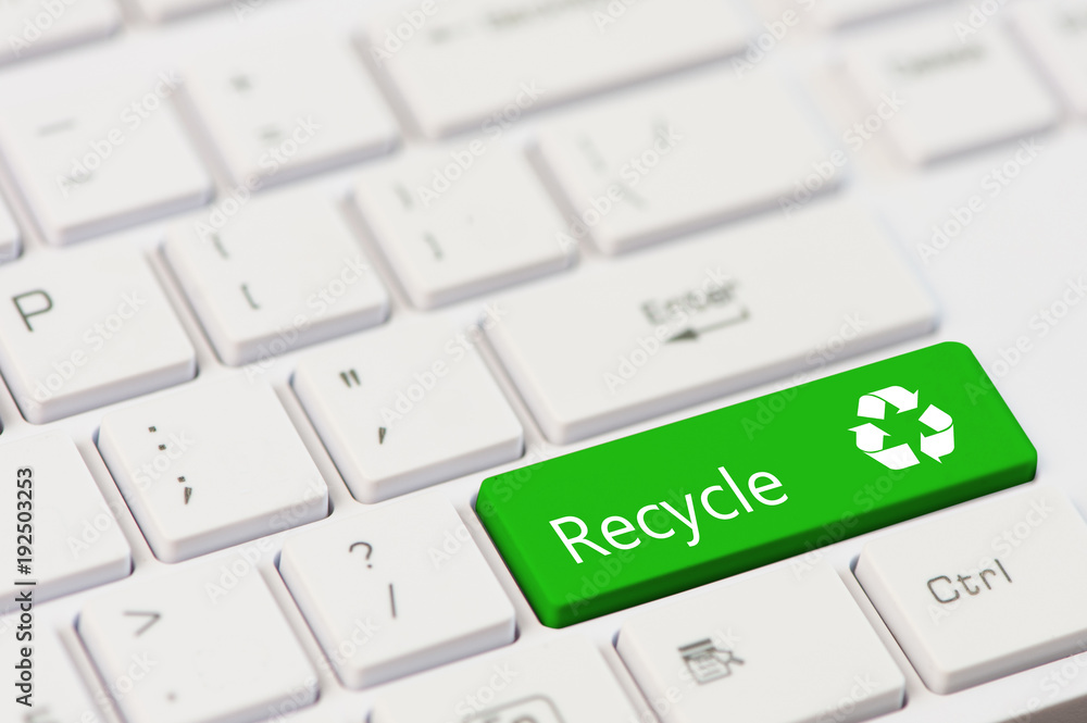 A green key with recycle icon symbol on white laptop keyboard. A green key with recycle icon symbol on white laptop keyboard.