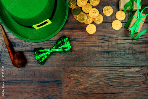 Saint Patrick's Day. Green hat of leprechaun, green bow tie, smoking pipe and gold coins on wooden background photo