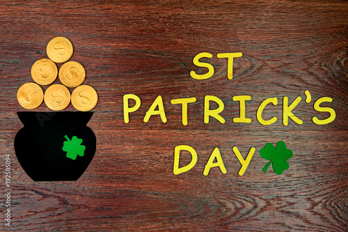 Saint Patrick's Day. Pot of Leprechaun with gold coins, gold wooden letters "ST Partick's Day" with green three petal luck clover on wooden background