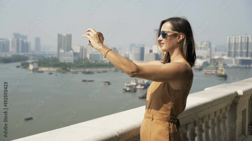 Young woman taking photos of cityscape with cellphone standing on terrace in city
Young woman taking photos of cityscape with cellphone standing on terrace in city