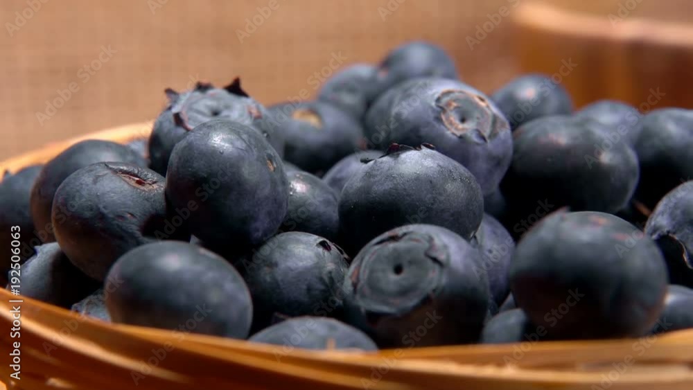 Hand puts a juicy ripe blueberry in a wicker basket Hand puts a juicy ripe blueberry in a wicker basket
