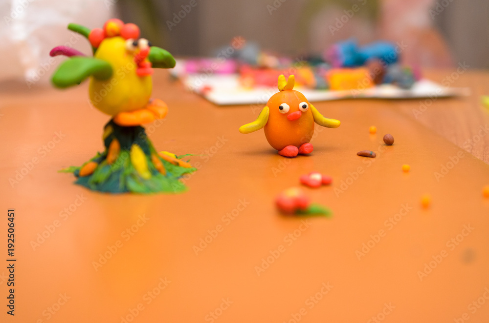 Rooster and chicken from plasticine on a yellow background.