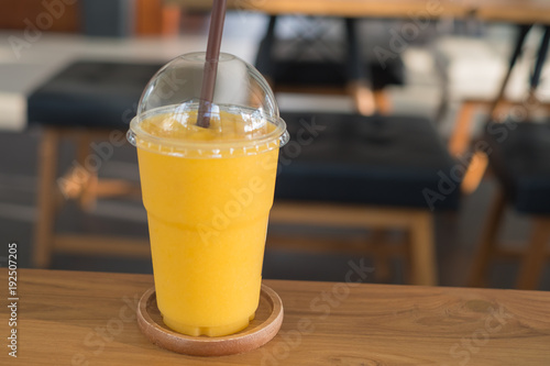 Sweet yellow mango smoothie on wood table in coffee shop