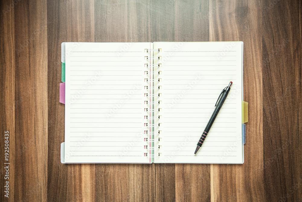 Pen and notepad on a wood background. Pen and notepad on a wood background.