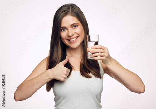 Smiling woman holding water glass showing thumb up.