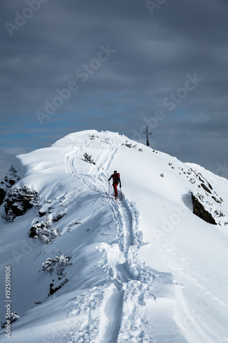 Sportler erreicht Gipfel bei einer Skitour im Winter