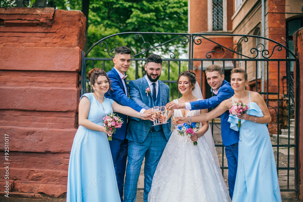 Fototapeta premium beautiful newlyweds with their friends having fun together. Friendship picture. Bridesmaids and groomsmen with bride and groom. Drinking champagne.