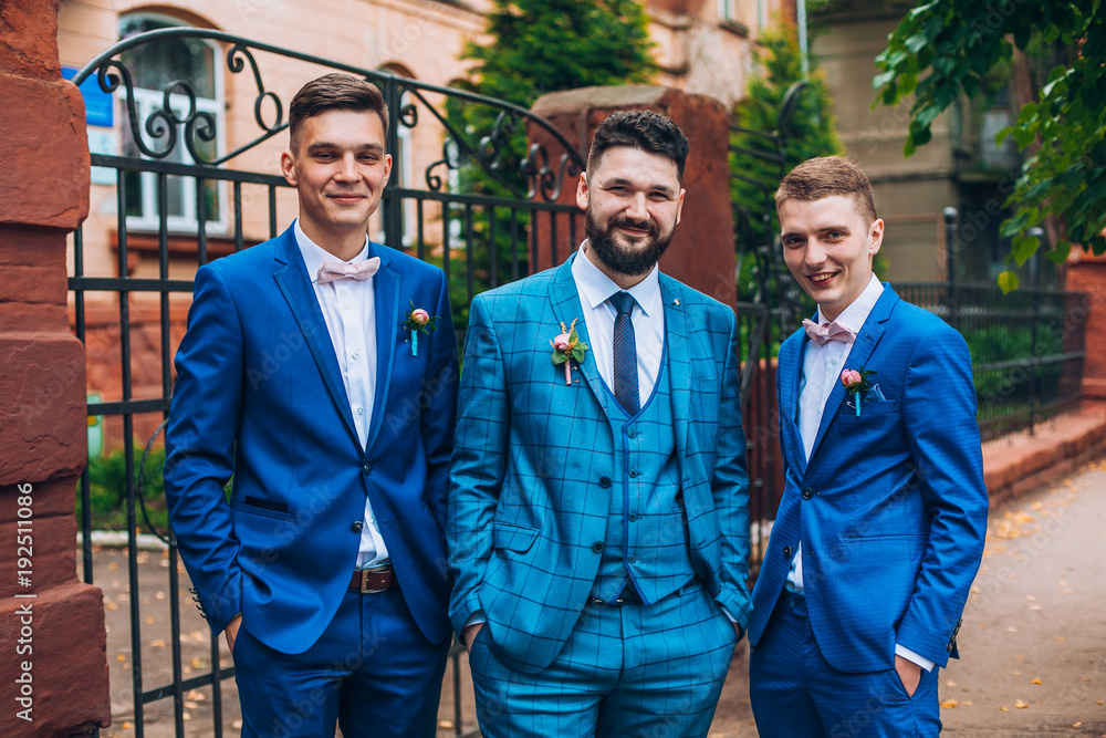 Groom and groomsmen look funny standing in the garden. Best friends on wedding day.