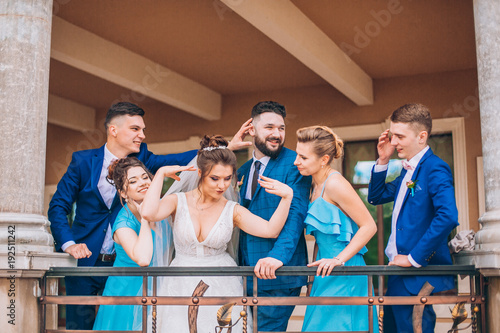 Full length portrait of newlywed couple and their friends at the wedding party. Bridesmaids and groomsman with Bride and groom near columns 