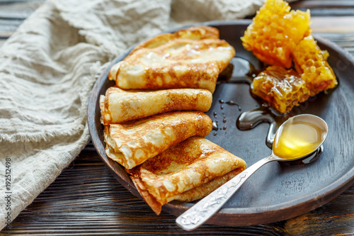 Crepes with honey on a wooden plate.