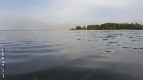 Blue water and sky with clouds over it. View over the water surface in nature