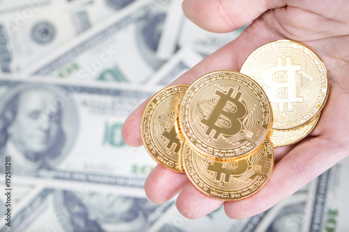 Bitcoin in female hand on dollar banknotes background