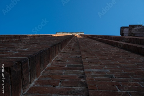 looking up on a building into the blue sky of Italy, tower of Venice, bricks wall with blue sky