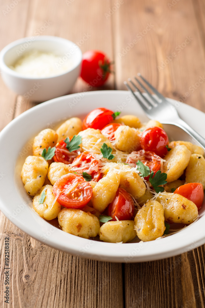 Homemade italian gnocchi with tomato, garlic, parsley and parmesan cheese on wooden table. Homemade italian gnocchi with tomato, garlic, parsley and parmesan cheese on wooden table.