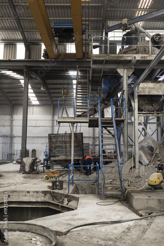 Factory indoors. Giant industrial mixer acces stairs, crane with concrete deposit photo