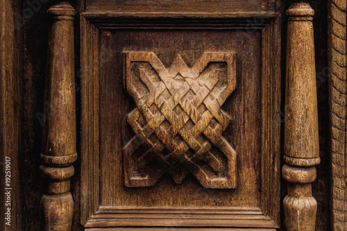 Vintage background. Elements of an old carved wooden door decorated with voluminous carved wooden elements imitating the weaving. A vintage concept of old antiques. Varnished old mahogany photo