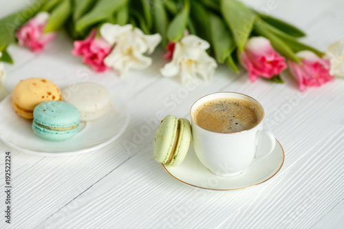Coffee, pink and white tulips and macarons on the white wooden table
